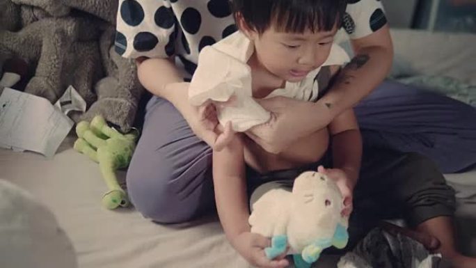 亚洲母亲在床上给男婴换衣服