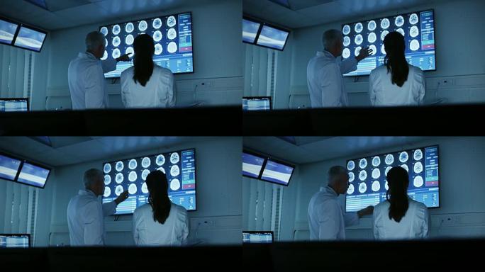 两位医学科学家/神经学家，在现代实验室中交谈并指向墙壁电视，显示CT/MRI脑部扫描。研究科学家在神