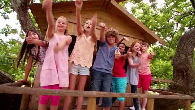 混合种族的儿童从木制树屋中挥舞
