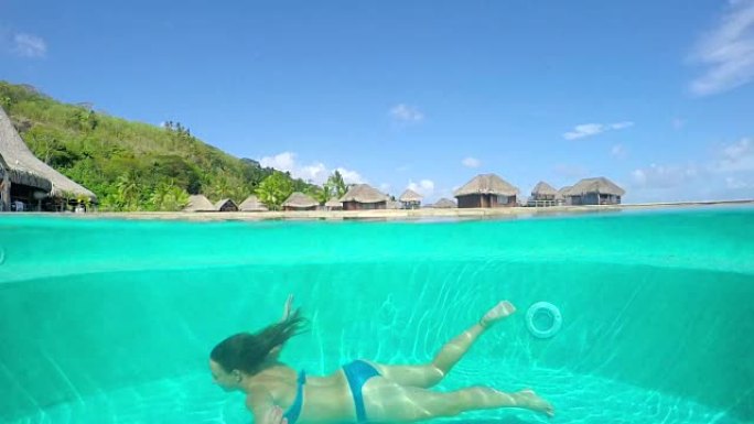水下: 女人在豪华酒店度假胜地的游泳池里游泳