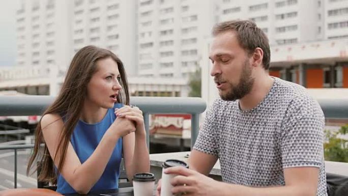 一对迷人的年轻夫妇在街上的一家咖啡馆里，一个女人在情感上向男人讲述了一些事情。全高清