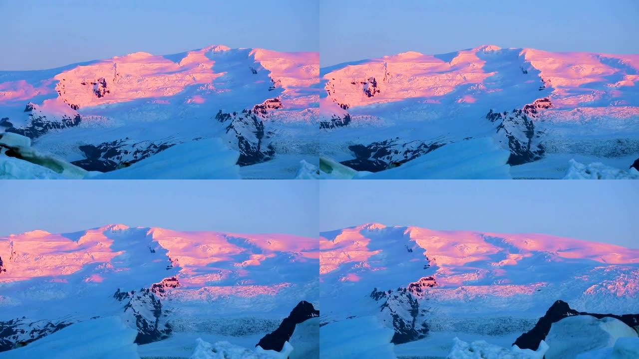 白雪皑皑的山峰上的粉色日出之光。