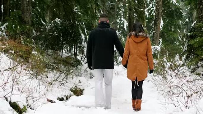 夫妇走在森林白雪覆盖的小路上