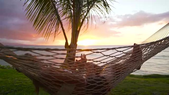 日落时在热带吊床上放松的浪漫情侣。夏季豪华假期。