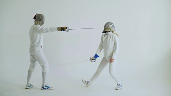 两名击剑手在白色背景上进行击剑训练攻击练习