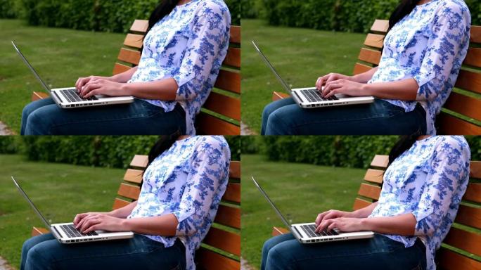 使用笔记本电脑坐在公园长椅上的女人
