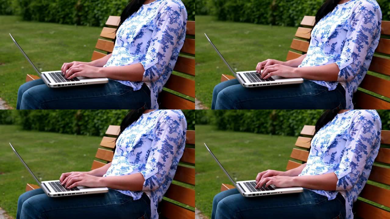 使用笔记本电脑坐在公园长椅上的女人
