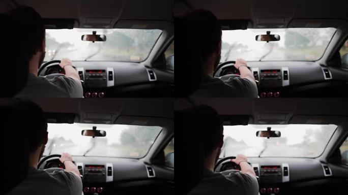 一个男人在雨中开车的背景图。手放在方向盘上，刮水器在工作