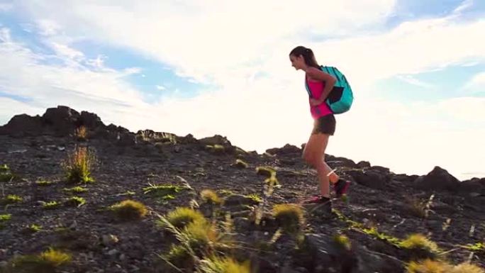 背包徒步旅行者带着太阳耀斑在山顶徒步旅行。年轻健康的女人在大自然中的冒险。