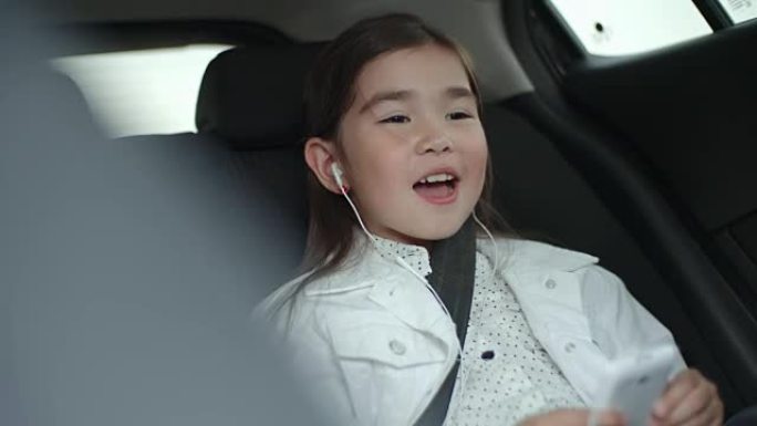 小女孩用智能手机在车里唱歌
