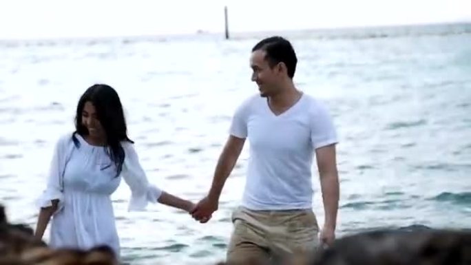 迷人的健康夫妇享受一起在海滩散步的时光。
