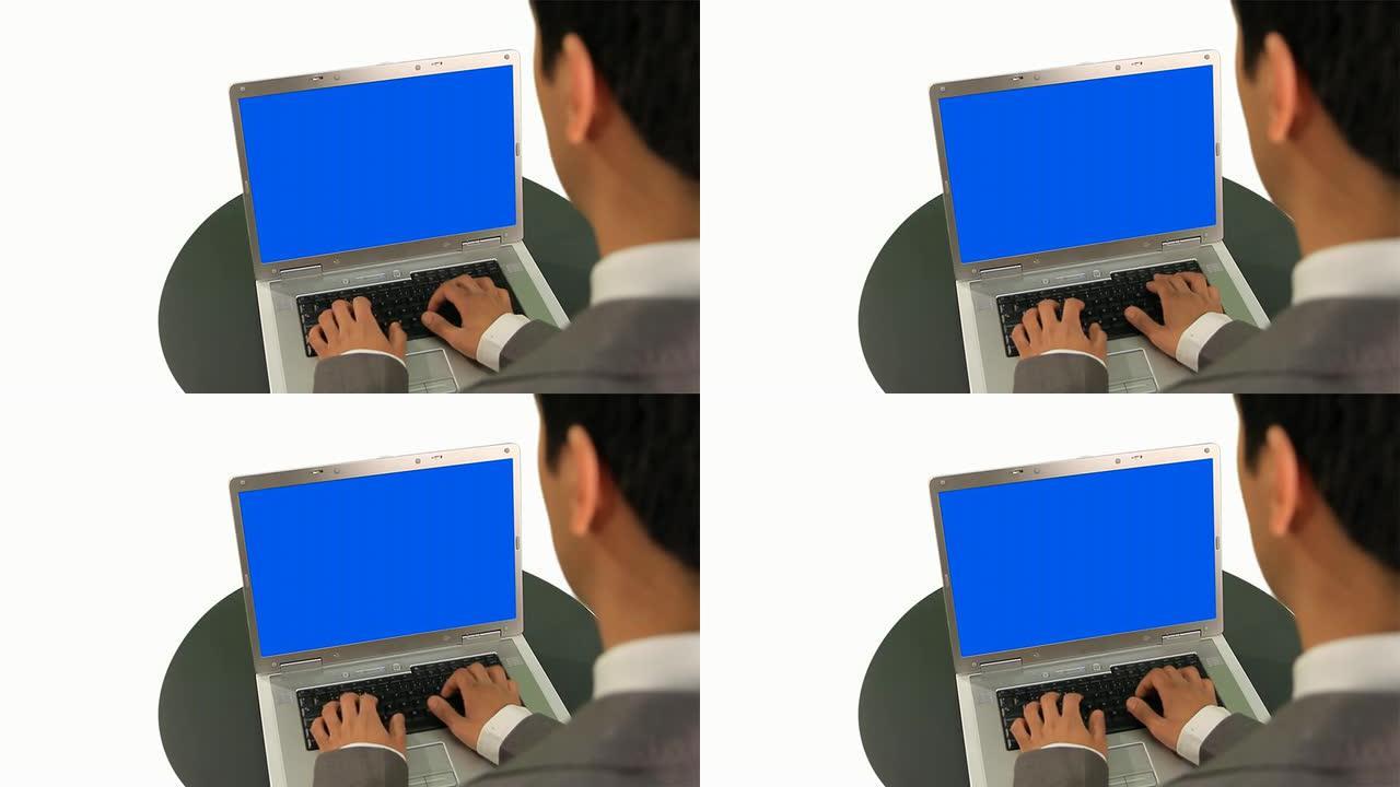 一名商人在一台彩色屏幕的笔记本电脑上打字