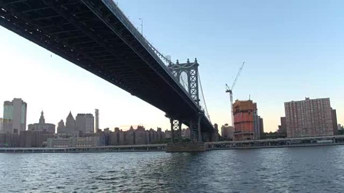 低角度视图: 在标志性的曼哈顿大桥下沿着东河巡游