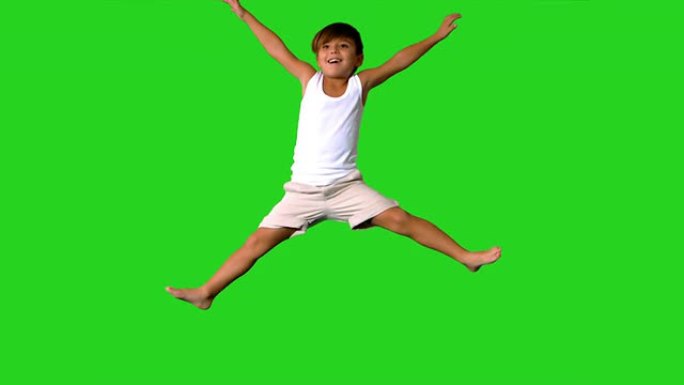 快乐的小男孩在绿色屏幕上跳跃