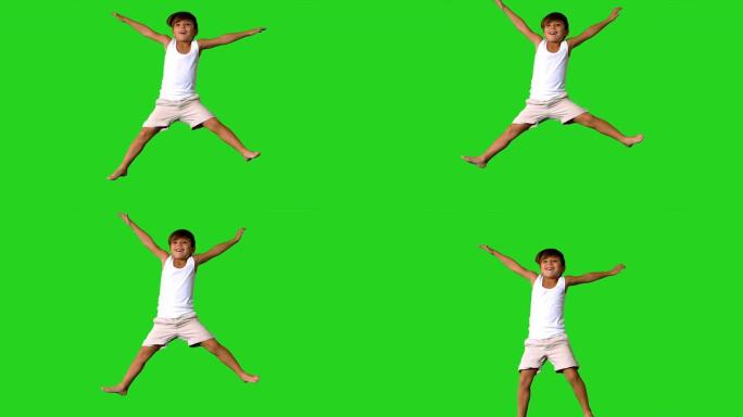 快乐的小男孩在绿色屏幕上跳跃