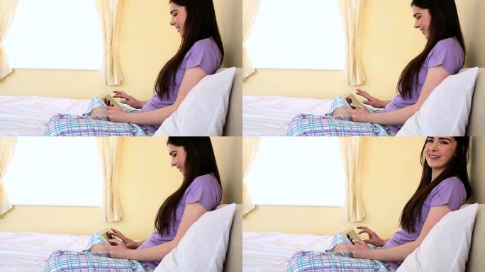 使用数字平板电脑的女人坐在床上