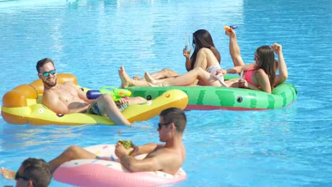 慢动作: 顽皮的年轻人在有趣的五颜六色的漂浮物上享受夏天