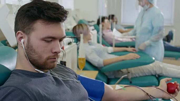 男人在献血时戴着耳机听音乐
