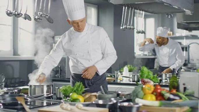 一家大餐厅的著名厨师在厨师的帮助下准备菜肴。现代厨房由不锈钢制成，充满烹饪原料。