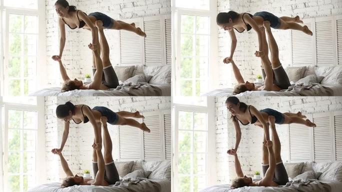 适合运动的年轻夫妇在床上一起练习acro瑜伽