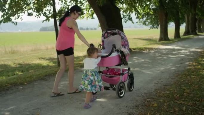 慢动作: 与妈妈一起散步时，推着婴儿车的小女孩向后看。
