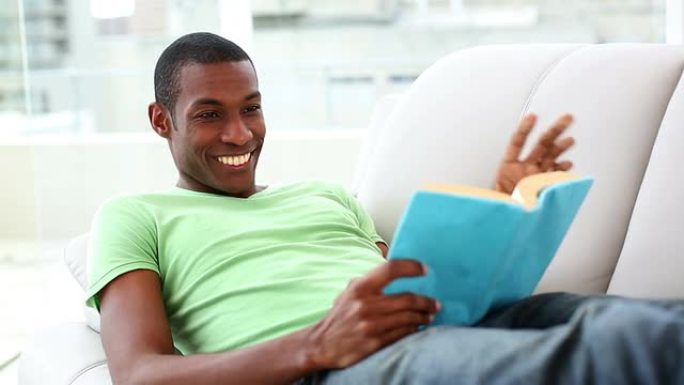 微笑的男人躺在沙发上看书