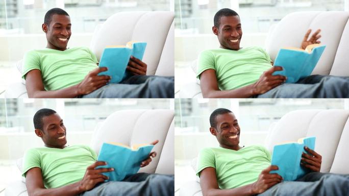 微笑的男人躺在沙发上看书