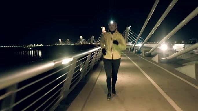 SLO MO Mid成年女子在桥上用头灯慢跑
