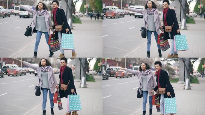 两名有吸引力的非洲裔美国妇女带着购物袋，从商场销售回来时叫出租车