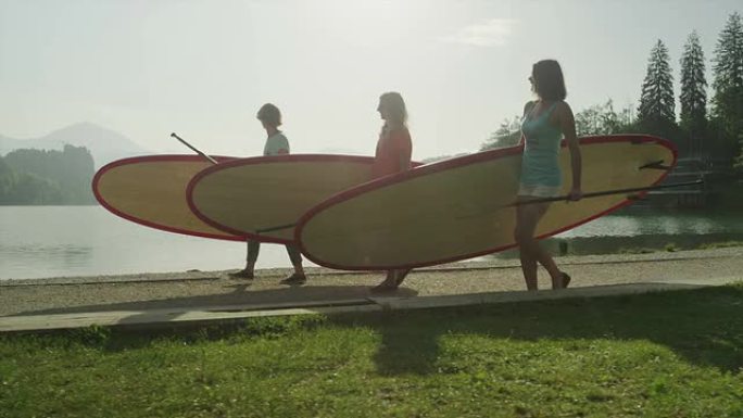 慢动作: 女孩在湖边背着SUP板