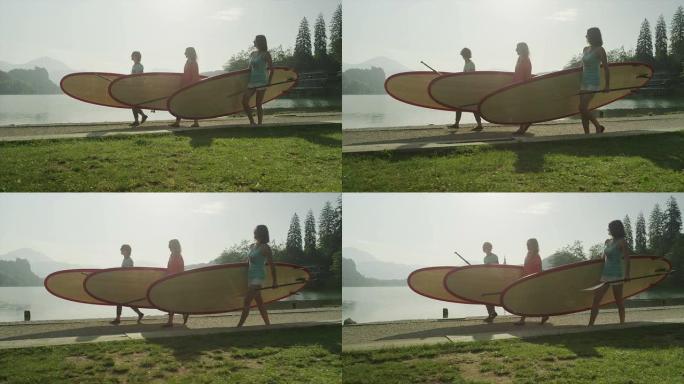 慢动作: 女孩在湖边背着SUP板
