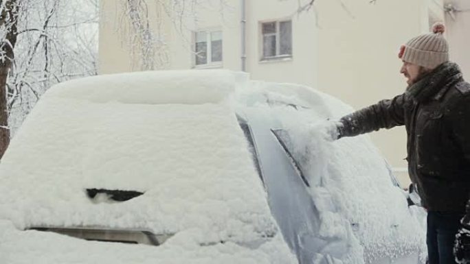 冬天，男子在街上清除汽车上的积雪，后视图