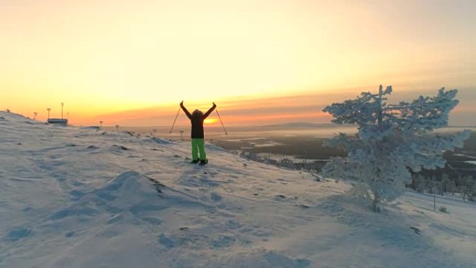 空中活跃的女人雪鞋在雪山斜坡上抬起手臂