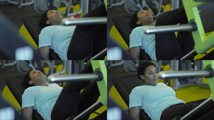 在健身房用压腿机锻炼的女人