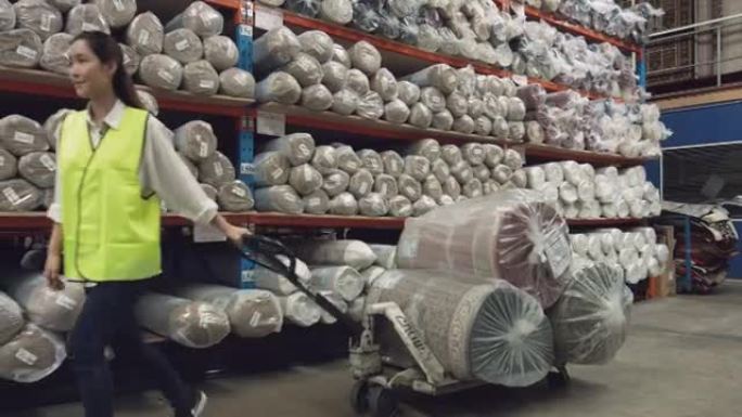 自信的亚洲女工人移动地毯在托盘千斤顶
