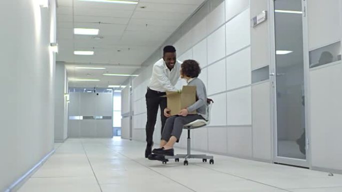 欢乐的男人在新办公楼与女同事推椅