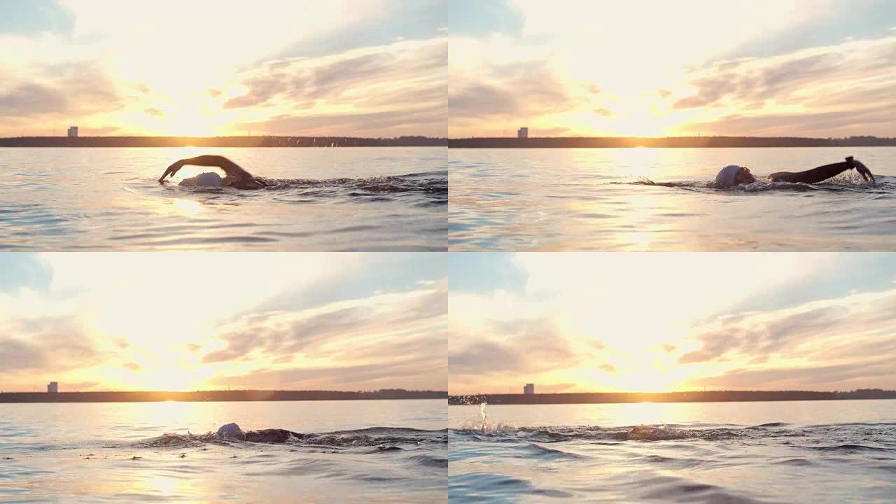 铁人三项游泳运动员在日落时在湖中练习