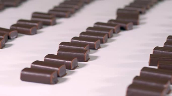 现成的巧克力糖果正在糖果工厂的生产线上移动。