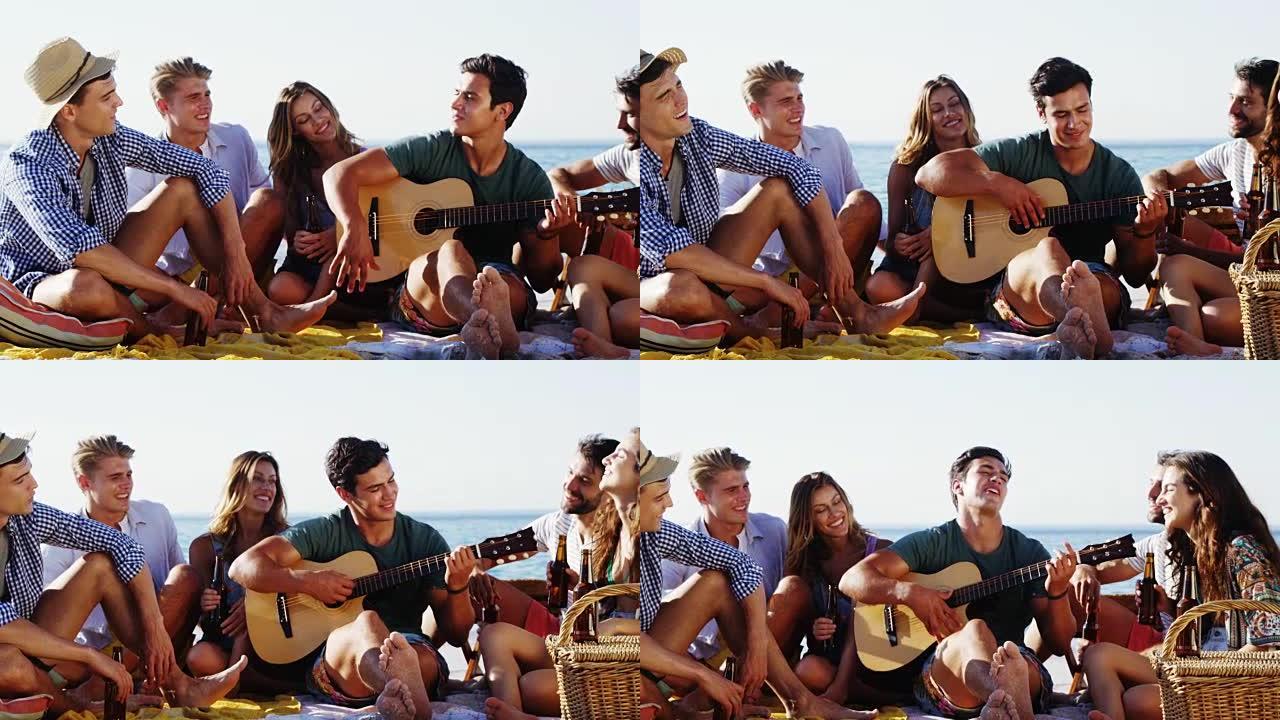男人为坐在沙滩上的朋友弹吉他4k