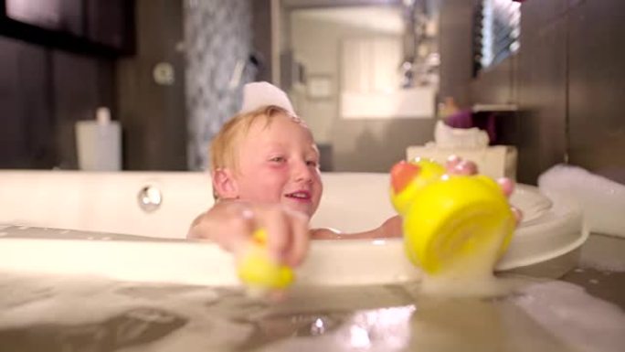 小男孩在泡泡浴中玩橡皮鸭