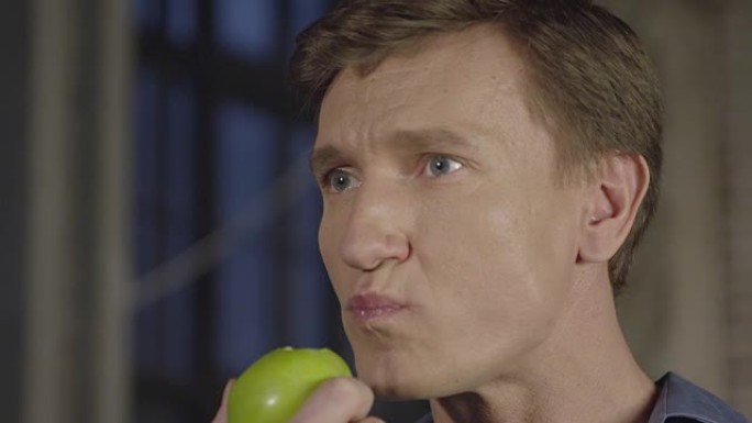 一个男人吃苹果的慢动作肖像。