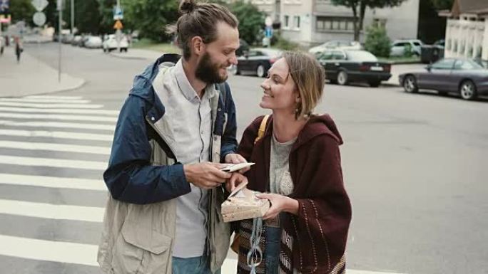 年轻幸福的夫妇拿着棋盘游戏的盒子。时髦的男人和女人在市中心玩任务