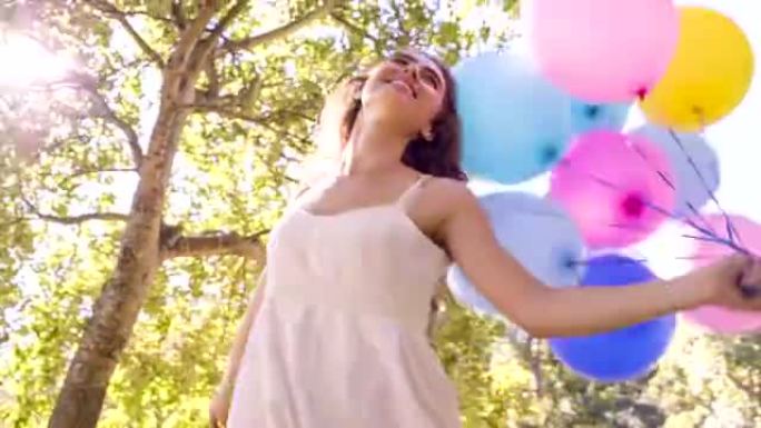 女人在公园里带着五颜六色的气球散步