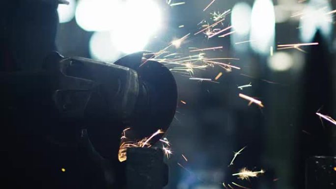 角磨机工人在工业环境中进行金属加工。火花反射
