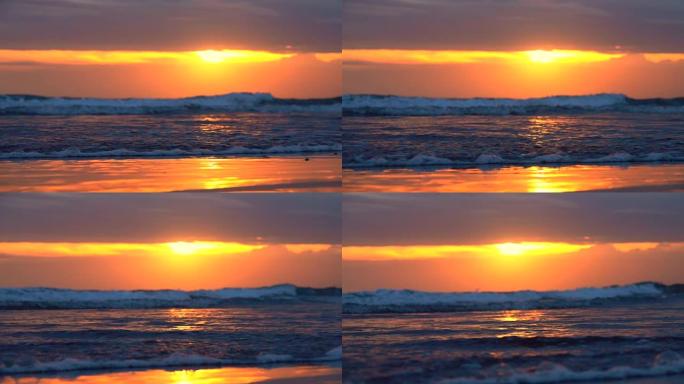 特写: 荡漾的海浪在巴厘岛引人注目的粉红色日落时冲刷沙滩