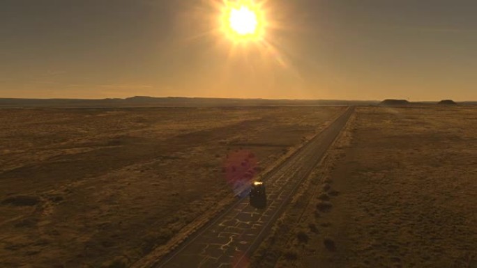 空中: 黑色SUV汽车在阳光明媚的早晨驶过空旷的沙漠高速公路