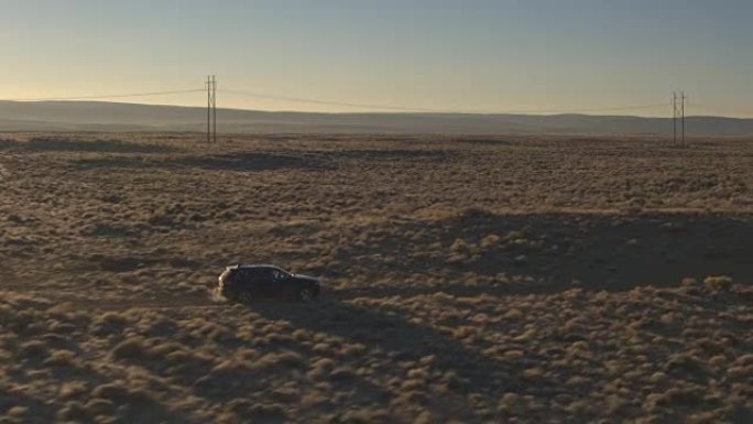 图片:在阳光明媚的夜晚，一辆黑色越野车行驶在火山茂密的沙漠中