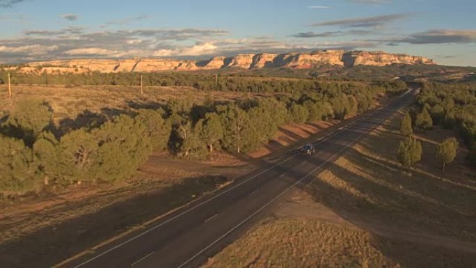 空中: 黑色SUV吉普车沿着空旷的道路行驶，在犹他州阳光明媚的风景中