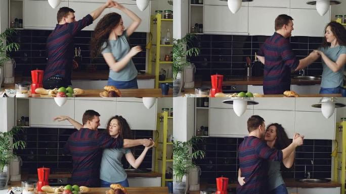 迷人的年轻快乐夫妇在家里厨房做饭时跳舞很开心