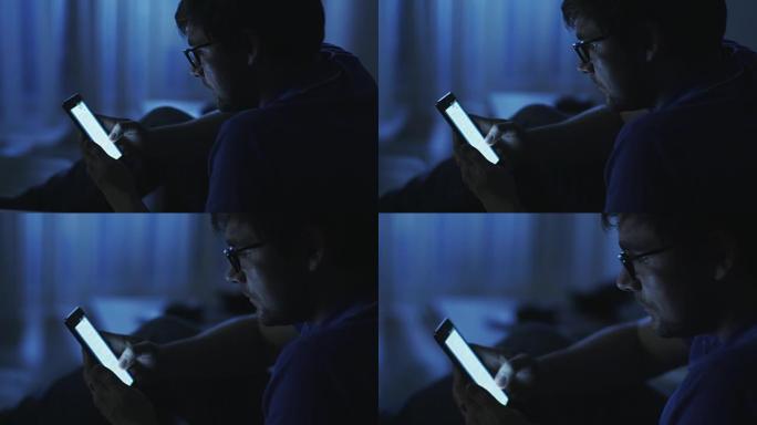 男人晚上在电话上浏览互联网